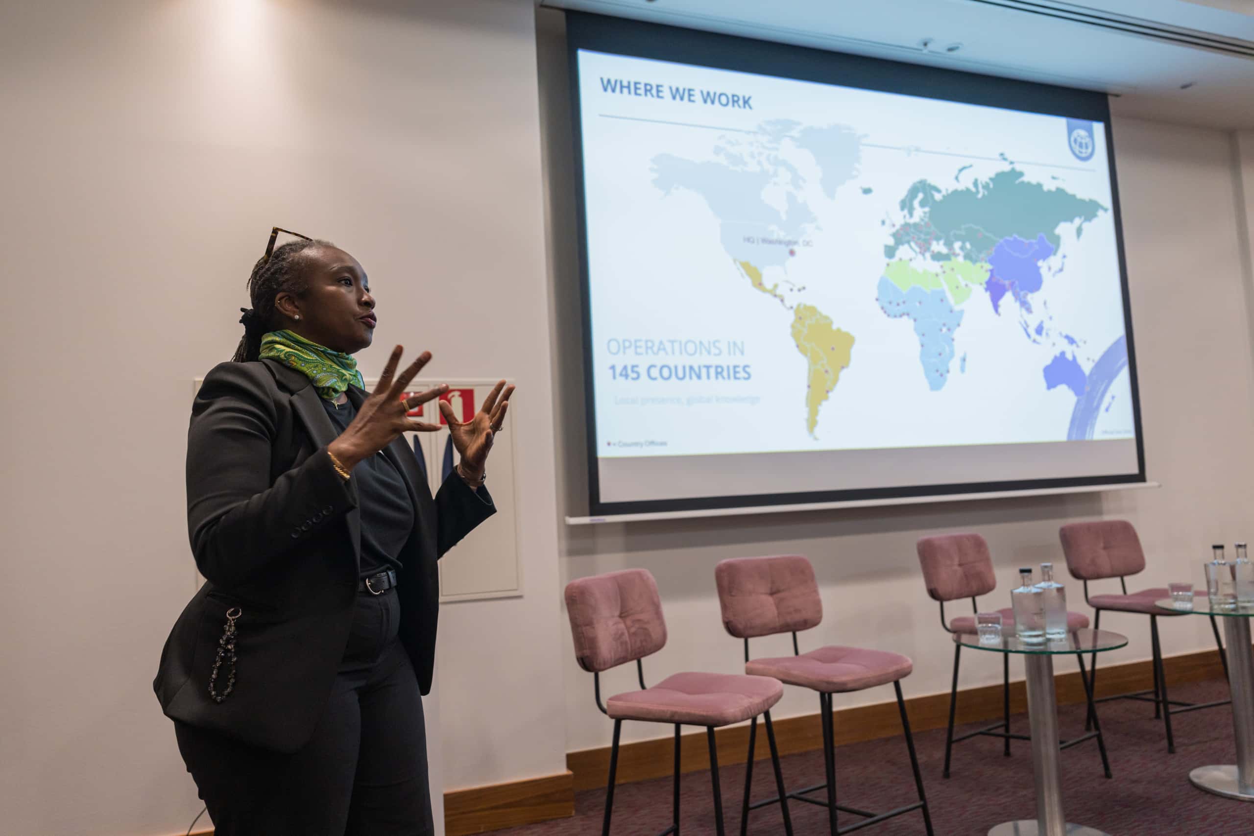 Foto van Fanta Sow naast een scherm met daarop de powerpoint presentatie